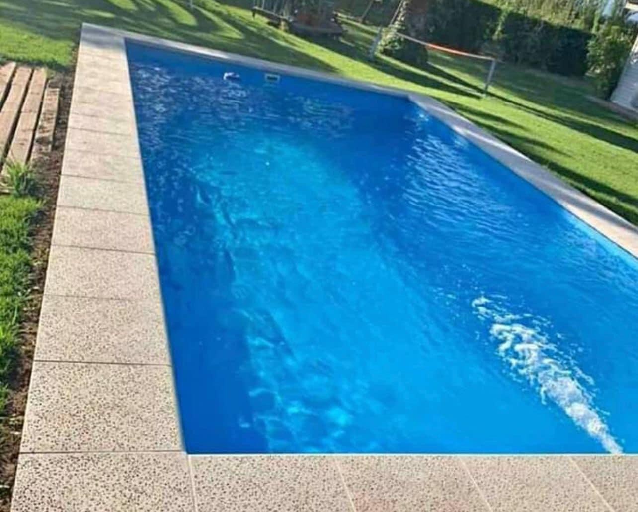 Piscina terminada con bordes claros junto al jardín